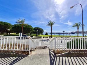a white fence with palm trees and a street light at Apartamento en la playa! in Sanxenxo