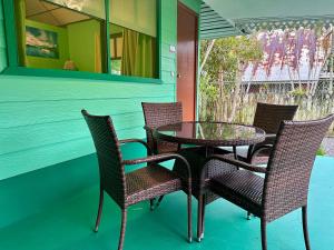 a glass table and chairs on a porch at « Le Green House » by Meri lodge Huahine in Fare