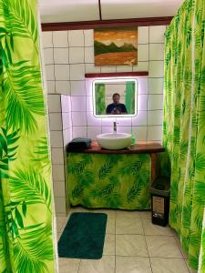 un hombre tomando una foto en un espejo del baño en « Le Green House » by Meri lodge Huahine, en Fare