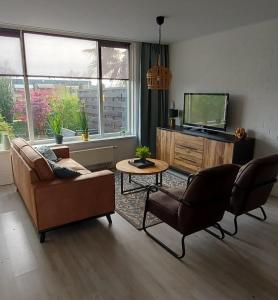 ein Wohnzimmer mit einem Sofa, Stühlen und einem TV in der Unterkunft Plattedijk - vakantiehuis 25-41 in Lemmer