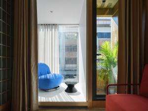 a room with a blue chair and a window at Stupid Stay in Bangkok