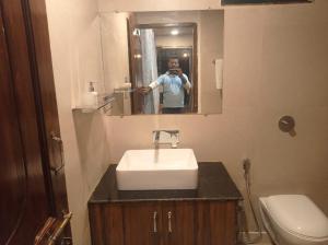 un uomo che scatta una foto di un bagno con lavandino di The Palash Vann Pench a Khawāsa