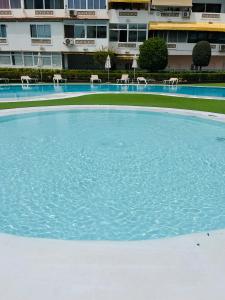 una gran piscina de agua con sillas y un edificio en Lovely apartment Taidia, en Maspalomas