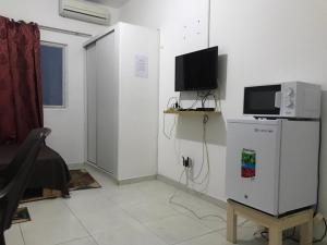 a living room with a tv and a refrigerator at 2SB Hospedagem in Praia