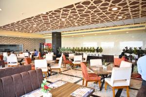 a restaurant with tables and chairs and people in the background at Hotel krishna in Nizāmābād