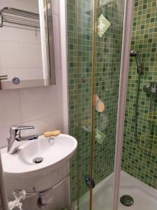 ein grün gefliestes Bad mit einem Waschbecken und einer Dusche in der Unterkunft Apartamento Coral con vistas al mar in Playa de Gandia