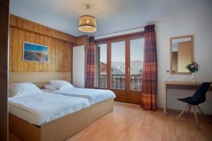 a bedroom with two beds and a desk and a window at Hotel la Rotonde in Verbier