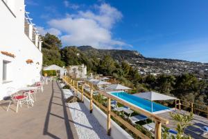 a resort with a pool and tables and umbrellas at Dimora Maiuri L'Olivella in Anacapri