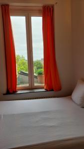 - une chambre avec un lit et une fenêtre avec des rideaux rouges dans l'établissement Antique appartement au centre d'Andenne, à Andenne