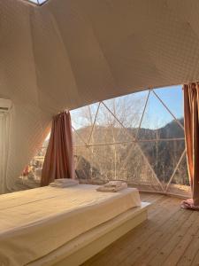 Bett in einem Zimmer mit einem großen Fenster in der Unterkunft Mountain View Hotel Complex in Yabulkovets
