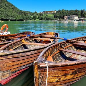 three wooden boats are docked on the water at Grand Hotel Astoria in Lavarone