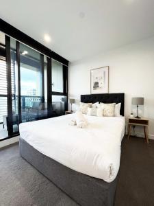 a large white bed in a room with large windows at Myka Home New Apartment in Box Hill YS4A in Box Hill