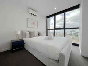 a bedroom with a white bed and a large window at Myka Home New Apartment in Box Hill YS4A in Box Hill