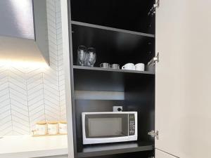 a microwave on a shelf in a kitchen at Myka Home New Apartment in Box Hill YS4A in Box Hill +6 photos
