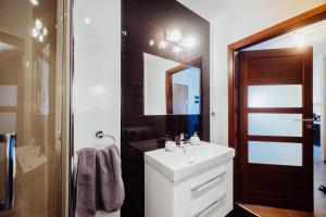 ein Badezimmer mit einem weißen Waschbecken und einem Spiegel in der Unterkunft 1 Maja 76 in Jelenia Góra + 17 Fotos