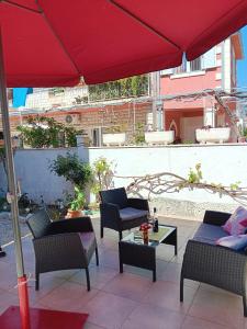 a patio with a red umbrella and chairs and a table at Apartman Mir in Kaštela +62 photos