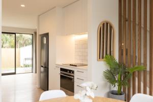 cocina con paredes blancas, mesa y sillas en Addington SOHO Two Bedroom Townhouse en Christchurch