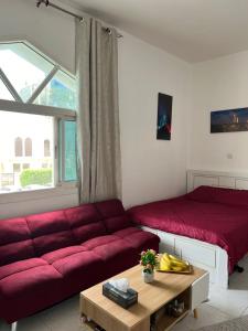 - un salon avec un canapé rouge et un lit dans l'établissement Lusy's studio Family Park, à Abu Dhabi