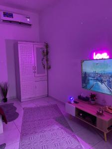 Habitación púrpura con TV y mesa. en Lusy's studio Family Park, en Abu Dabi