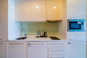 cocina con armarios blancos, fregadero y microondas en eStay Residence·Poly World Trade Center Guangzhou, en Guangzhou