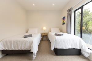 2 camas en una habitación blanca con ventana en Addington SOHO Two Bedroom Townhouse en Christchurch