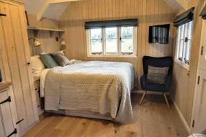 a bedroom with a bed and a chair at Cabin in the Woods in Ardingly
