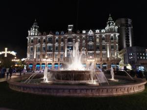 una fontana di fronte a un grande edificio di notte di Habitacion matrimonial centro ciudad a Oviedo