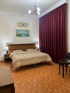 1 dormitorio con 2 camas y cortinas rojas en Sufara Hotel Suites, en Amán
