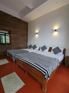 2 Betten in einem Zimmer mit Ziegelwand in der Unterkunft Diduli Hotel in Ella