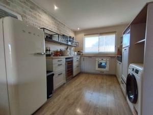 uma cozinha com um frigorífico branco e piso em madeira em Villa grande terrasse avec jacuzzi em Palavas-les-Flots