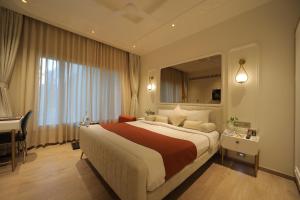 ウダイプールにあるAmantra Comfort Hotelの大きなベッドと机があるホテルの部屋 +96枚の写真