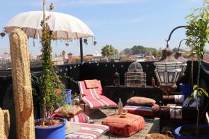 a balcony with chairs and an umbrella on a roof at Dar Didifa in Marrakesh