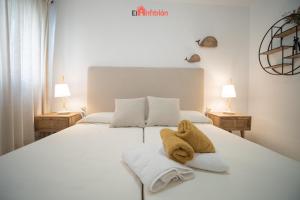 ein Schlafzimmer mit einem weißen Bett und Handtüchern darauf in der Unterkunft El Anfitrión - Casa Dunas in Sanlúcar de Barrameda