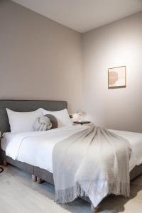 um quarto com uma cama grande e lençóis brancos em Minilove Homestay em Tainan