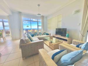 a living room with couches and a television with a view at Luxury at Fynbos 5 in Mossel Bay