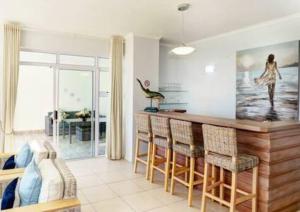 a kitchen with a bar with chairs and a table at Luxury at Fynbos 5 in Mossel Bay