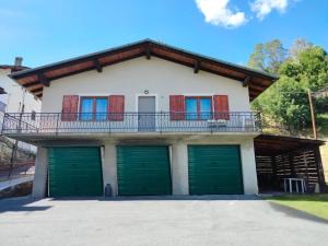 a house with green garage doors and a balcony at Casa singola totalmente indipendente in Introd