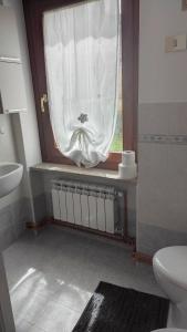 a bathroom with a toilet and a window with a curtain at Casa singola totalmente indipendente in Introd