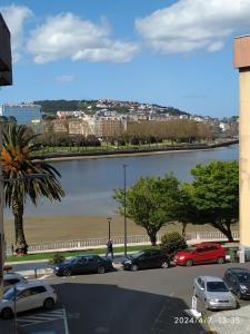 a parking lot with cars parked next to a body of water at Ría del Burgo in Cambre