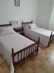 Un dormitorio con dos camas y una mesa con lámpara. en Casa Fariña, en Muxía