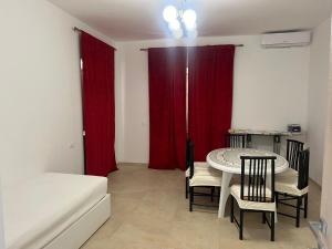 スペルロンガにあるSperlonga Apartmentのテーブルと椅子、赤いカーテンが備わる客室です。