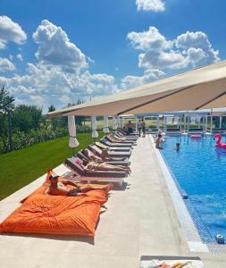 un grupo de personas tumbadas en las camas junto a una piscina en Hotel Goya Boutique, en Târgu Jiu