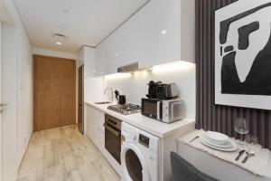 a kitchen with a washer and dryer and a microwave at Luxury Redefined in AHAD Residence by Suiteable in Dubai
