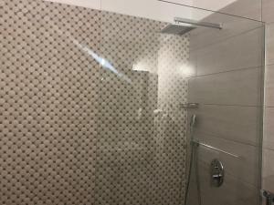 y baño con ducha y pared de azulejos. en Saranda Hotel, en Sarandë