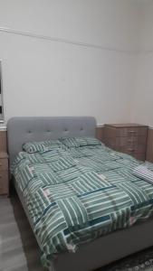 un letto con una coperta verde e blu sopra di Spacious one bedroom flat w/ parking a Walsall