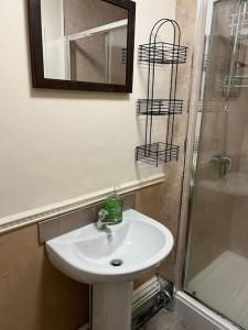 La salle de bains est pourvue d'un lavabo, d'un miroir et d'une douche. dans l'établissement Spacious one bedroom flat w/ parking, à Walsall