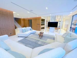 ein Wohnzimmer mit weißen Möbeln und einem TV in der Unterkunft ULTRA Modern Villa Manresa with Private Beach & Infinity Pool on Palm Island in Dubai