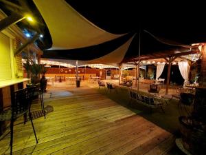 a deck with tables and chairs and an umbrella at Le Baraillot, Chambres et repas d'hôtes, soirée étape in Aiguillon