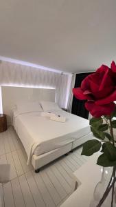 Cama blanca en habitación con rosa roja en Q Hotel, en Rímini
