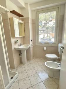 La salle de bains est pourvue d'un lavabo, de toilettes et d'une fenêtre. dans l'établissement Appartamento tra lago&montagna, à Taceno